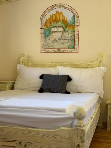 a bed with white pillows and a picture on the wall at Villa Melnik SPA Residence with Hot Pool by BookVillaBG in Melnik