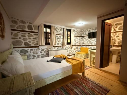 a bedroom with a bed and a stone wall at Villa Melnik SPA Residence with Hot Pool by BookVillaBG in Melnik