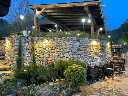 a stone wall with chairs and a table and a building at Villa Melnik SPA Residence with Hot Pool by BookVillaBG in Melnik