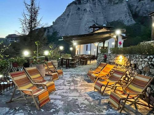 a group of chairs and tables with a mountain in the background at Villa Melnik SPA Residence with Hot Pool by BookVillaBG in Melnik