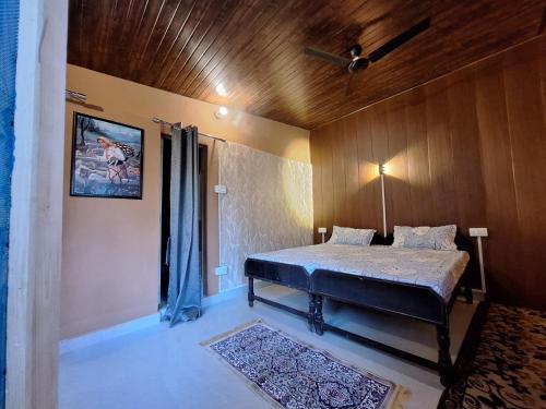 a bedroom with a bed and a wooden ceiling at TATHASTU Bir -Homestay ,DORM,HOSTEL in Bīr