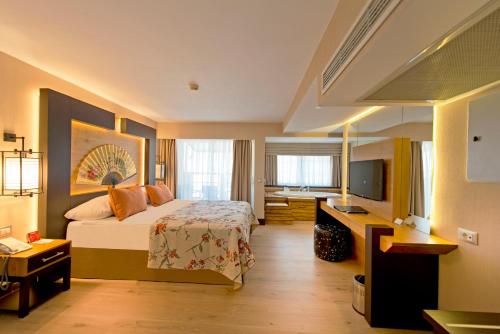 a hotel room with a bed and a television at Limak Lara Deluxe Hotel & Resort Antalya in Lara