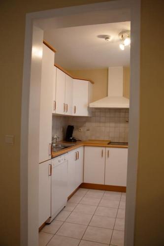 a kitchen with white cabinets and a white tile floor at Séjour en bord de Meuse avec garage in Dinant
