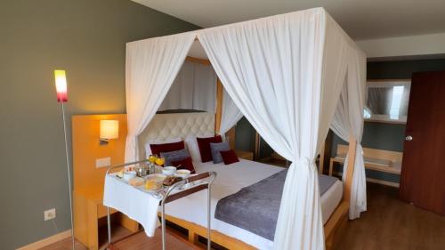 a bedroom with a canopy bed and a table with food on it at Hotel Atlantida Sol in Figueira da Foz