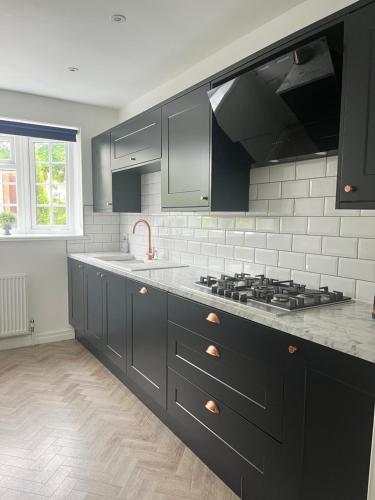 a kitchen with black cabinets and a stove at The Nutshell in Southport