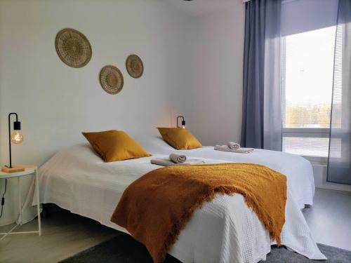 a bedroom with a large white bed with orange pillows at Kampuksen Tähti in Pori