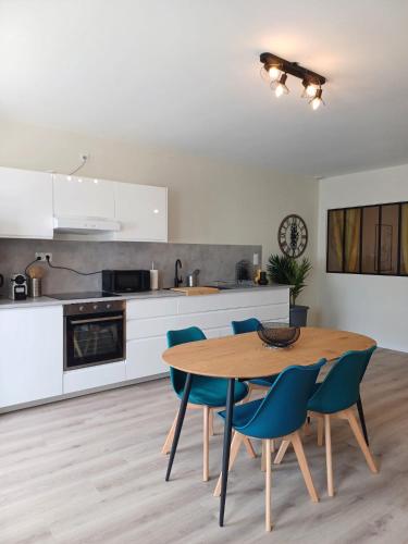 une cuisine avec une table en bois et des chaises bleues dans l'établissement T3 du canal, 2chs, 2 sdb, 3 lits, à Agen