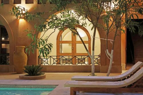 a pool with trees and a bench and a window at Malkata House - Boutique hotel and restaurant in Luxor