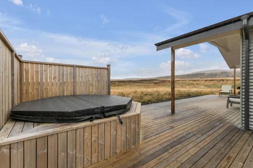 a bed on a wooden deck with a roof at 3BR Fishing Cabin with Hot Tub in Reykholt