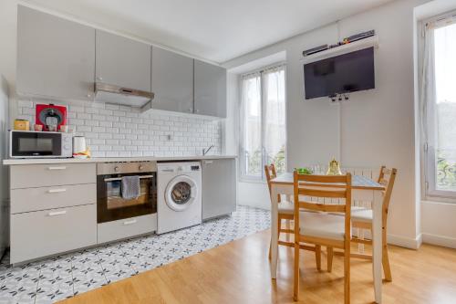 une cuisine avec des armoires blanches, une table et un micro-ondes dans l'établissement Tout équipé - Métro 7 à 1 min - Proche La Villette, à Aubervilliers