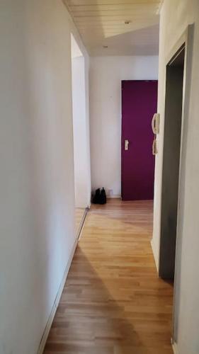 a hallway with a purple door and a wooden floor at Snuggly Spacious Apartment Near Everything in Landstuhl