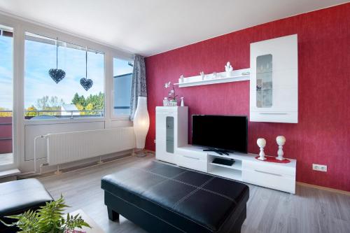 a living room with a tv and a red wall at Ferienwohnung Manuela in Sankt Englmar