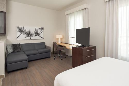 a hotel room with a bed a couch and a desk at Residence Inn by Marriott West Palm Beach Downtown in West Palm Beach