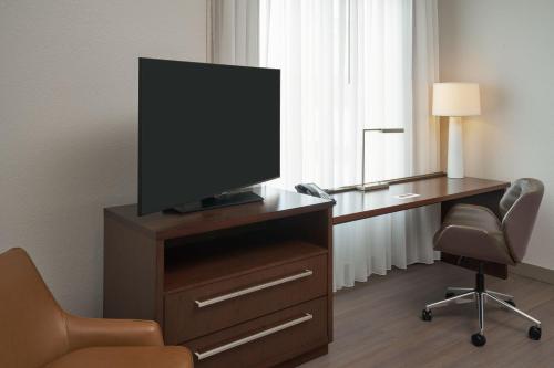 a television on a dresser with a desk and a chair at Residence Inn by Marriott West Palm Beach Downtown in West Palm Beach