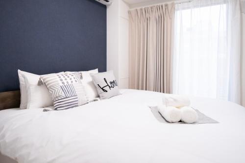 a bedroom with a white bed with pillows and a window at The Peak Tsutenkaku in Osaka