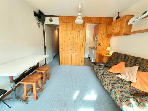 Cette chambre comprend un canapé, un bureau et une table. dans l'établissement Studio chaleureux à 100m des pistes, balcon exposé sud, casier à skis - FR-1-351-17, à La Plagne