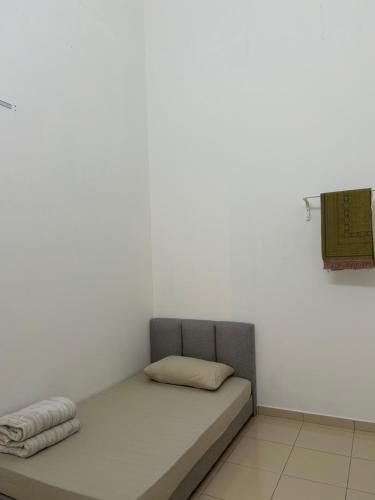 a bed in a room with a white wall at Homestay Taman Melati Jerantut in Jerantut