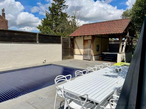 a white table and chairs next to a swimming pool at La villa d'exception Piscine Jacuzzi Sauna Hammam in Landen