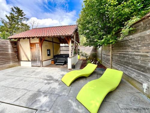 a patio with two green chairs and a house at La villa d'exception Piscine Jacuzzi Sauna Hammam in Landen