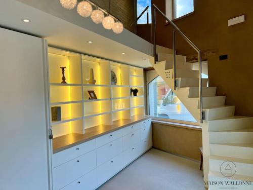 a staircase in a room with yellow walls and white cabinets at La villa d'exception Piscine Jacuzzi Sauna Hammam in Landen