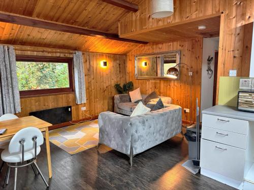 a living room with a couch and a table at Snowdrop 14 Hot tub-Woodlandlodges-Tenby-Pendine in Carmarthen