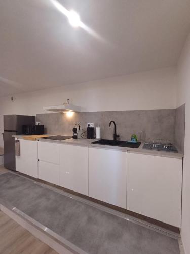 une cuisine avec des armoires blanches et un évier dans l'établissement le loft du canal, 2 lits, baignoire balnéo, wifi, à Agen
