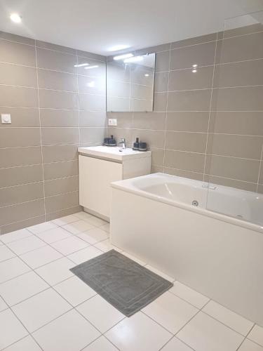 une salle de bain blanche avec une baignoire et un lavabo dans l'établissement le loft du canal, 2 lits, baignoire balnéo, wifi, à Agen
