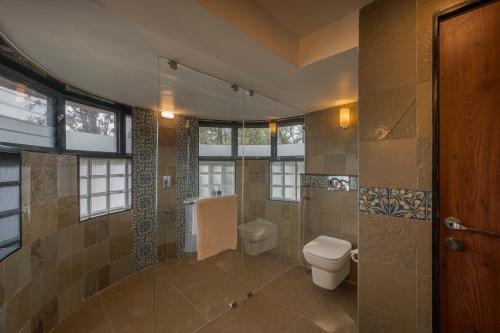 a bathroom with a toilet and a shower withwindows at SaffronStays Red Brick House, Panchgani - rustic villa with huge lawn and terrace in Panchgani