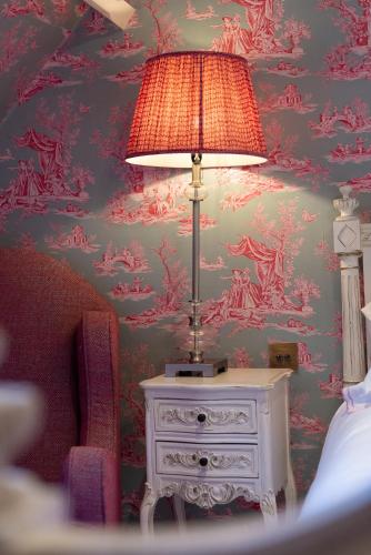a lamp on a table in a bedroom with a wallpaper at Gileston Manor Luxury B&B in Barry
