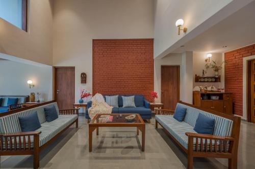a living room with blue couches and a table at SaffronStays Red Brick House, Panchgani - rustic villa with huge lawn and terrace in Panchgani