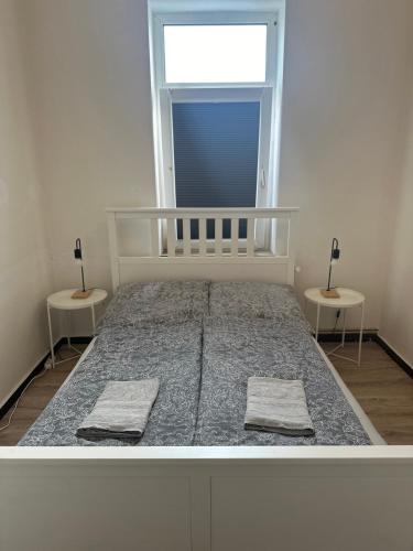 a bedroom with a bed with two tables and a window at Ferienwohnung Augustus in Bremerhaven