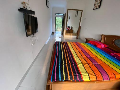 a bed with a colorful blanket on it in a room at Kamar no 4 in Sampal 2