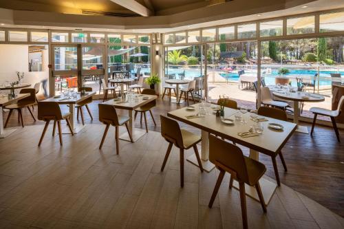 a restaurant with tables and chairs and a pool at Garrigae Domaine de l'Esterel - piscine & SPA Cinq Mondes in Saint-Raphaël
