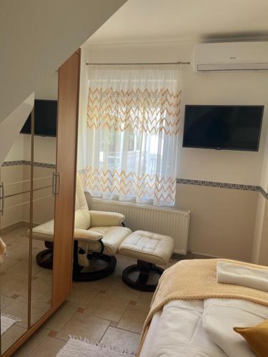 a bedroom with a bed and a chair and a window at Réka Apartmanház in Bük