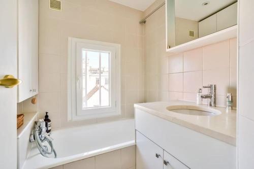 une salle de bain blanche avec un lavabo et une fenêtre dans l'établissement Montmartre, Patio! Sacré-Coeur! Stylish duplex!, à Paris