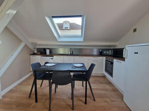 une cuisine avec une table et des chaises et une fenêtre dans l'établissement Appartement T2 Le central, à Chalon-sur-Saône