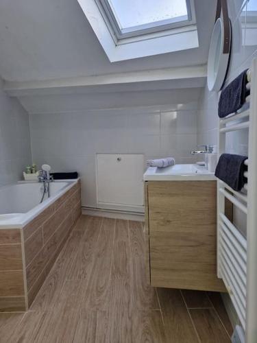 La salle de bains est pourvue d'une baignoire, d'un lavabo et d'une lucarne. dans l'établissement Appartement T2 Le central, à Chalon-sur-Saône