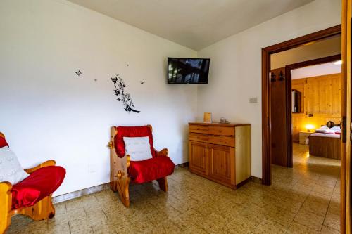 a living room with two chairs and a tv on the wall at Appartamenti Le Bistrot in Saint Nicolas