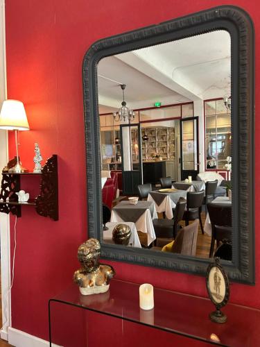 a mirror on a red wall with a dining room at Le Grand Hôtel Mont Dore in Le Mont-Dore