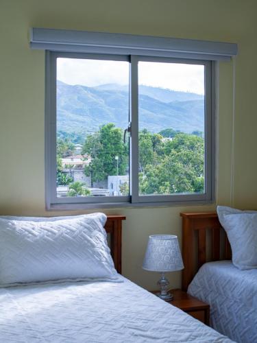 a bedroom with two beds and a large window at Villas Vallejuelo in Vallejuelo