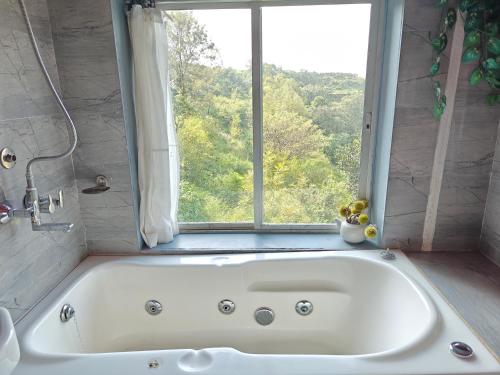 La salle de bains est pourvue d'une baignoire blanche et d'une fenêtre. dans l'établissement Tabletop Boutique Resort, à Panchgani