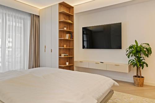 a bedroom with a bed and a tv on a wall at Studio Luxury Cortina North Residence Pipera in Voluntari