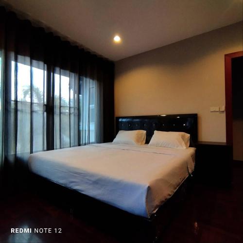 a large bed in a bedroom with a large window at CHILLI's Homes2 in Chiang Mai
