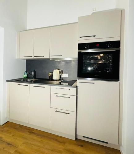 a kitchen with white cabinets and a black microwave at Pension Romantica in Rust
