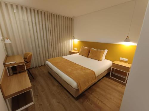 a hotel room with a large bed and two tables at Casa do Correio in Pampilhosa da Serra