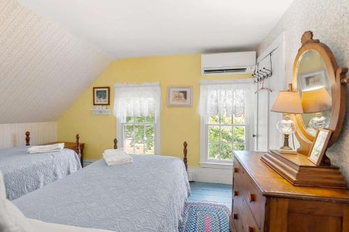 a bedroom with two beds and a mirror and a dresser at On the Chatham Loop - 1 Min to the Beach in Chatham