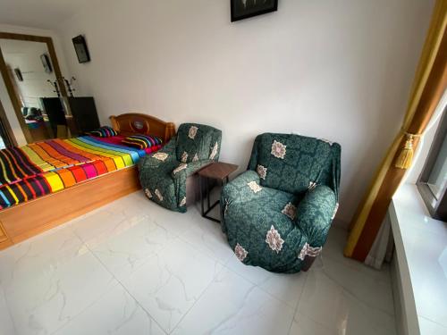 two chairs and a table in a room with a bed at Kamar no 5 in Sampal 2