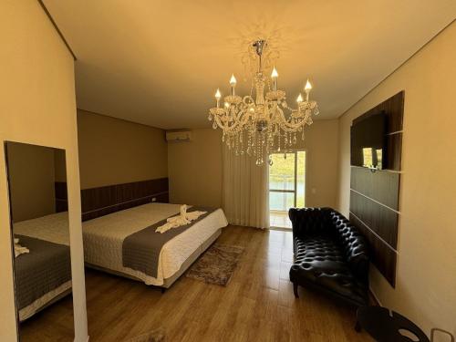 a bedroom with a bed and a chandelier at Hotel Beira Rio in Piraju