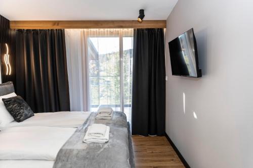 a hotel room with a bed and a large window at Apartamenty Bujaś Resort - Białka Spa Resort in Białka Tatrzanska