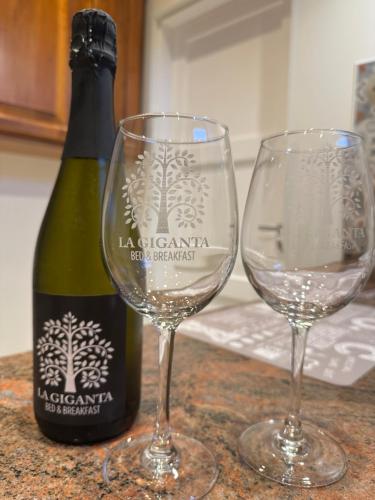 two wine glasses sitting next to a bottle of wine at B&B La Giganta in Porto Viro